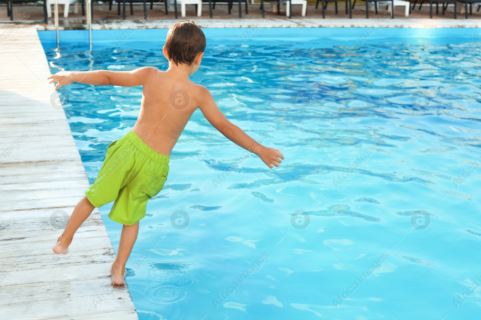 Photo of Little child jumping in outdoor swimming pool. Dangerous situation