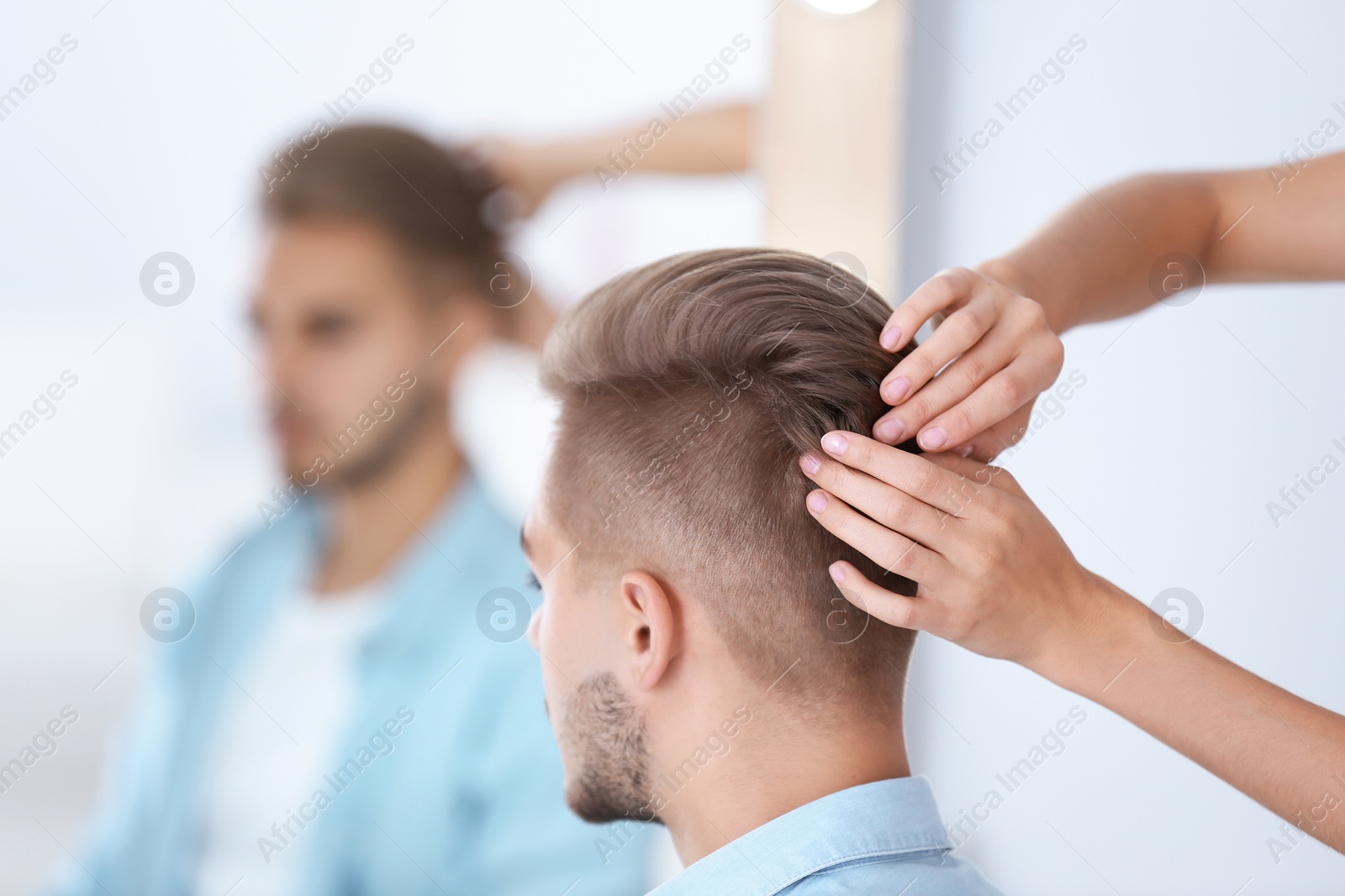 Photo of Professional hairdresser working with young man in barbershop. Trendy hair color