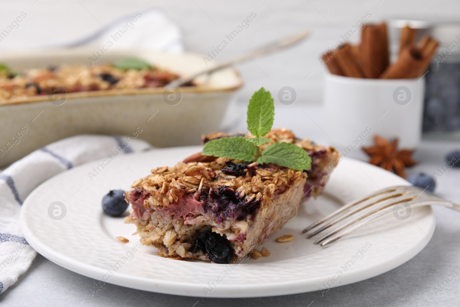 Photo of Tasty baked oatmeal with berries on light table, closeup