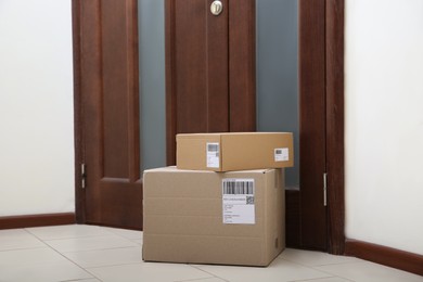 Photo of Stacked parcels near door on floor. Delivery service