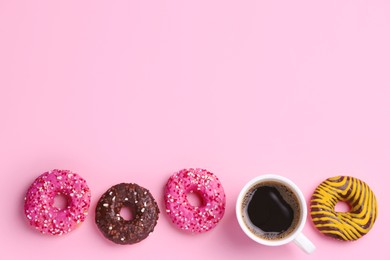 Photo of Tasty donuts and cup of coffee on pink background, flat lay. Space for text