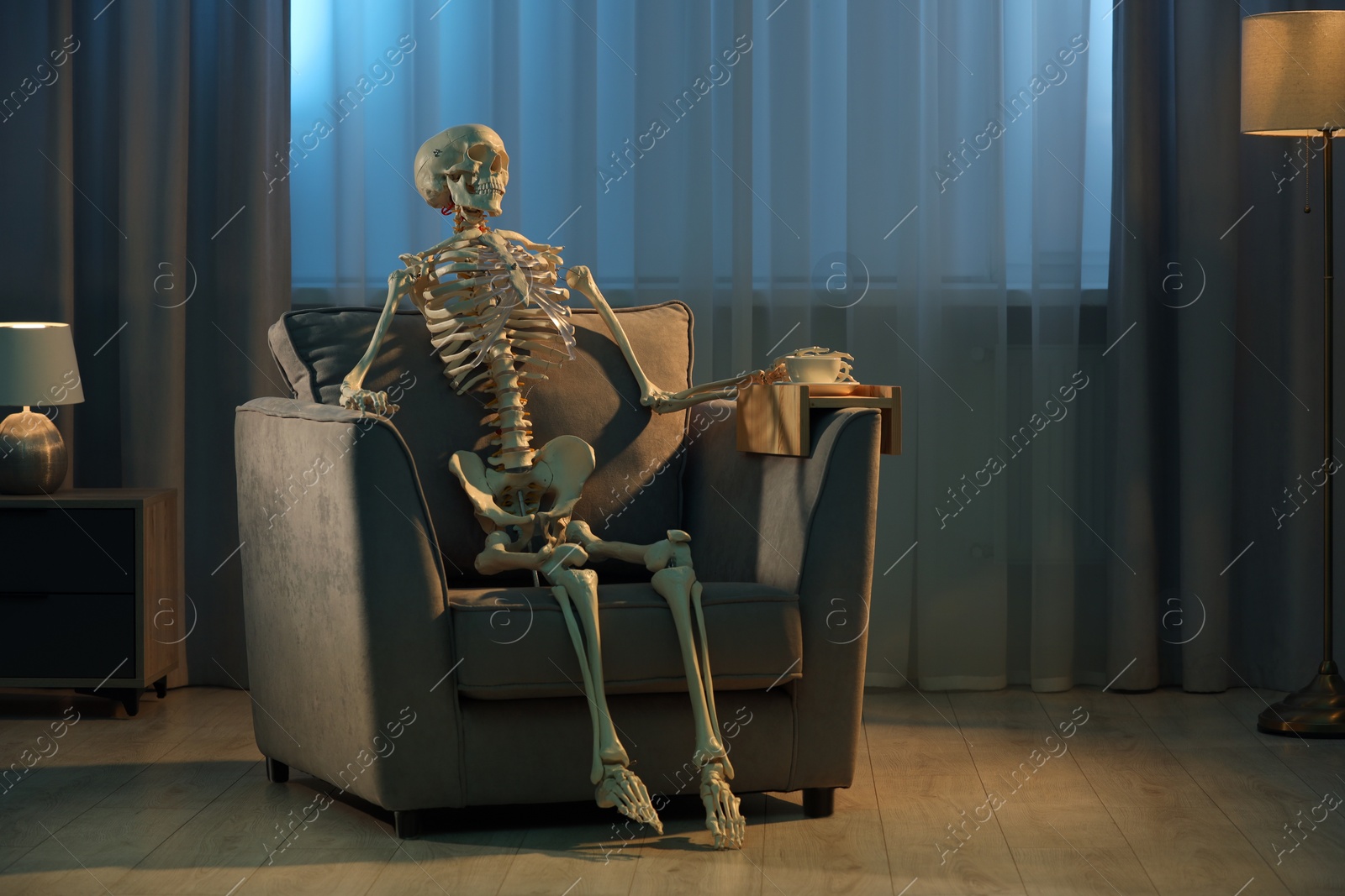 Photo of Waiting concept. Human skeleton sitting in armchair indoors