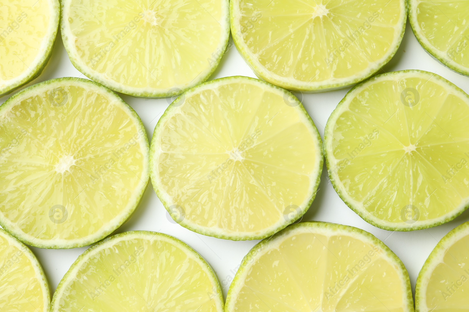 Photo of Fresh juicy lime slices on white background, flat lay