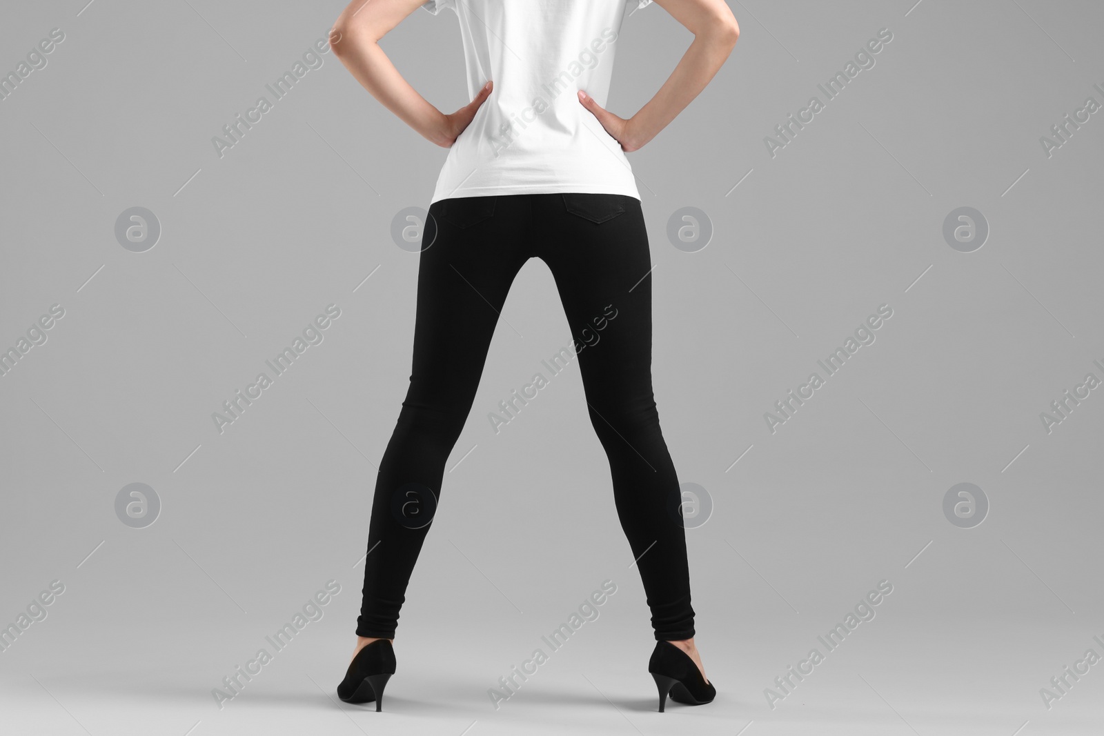 Photo of Woman wearing stylish black jeans and high heels shoes on light gray background, closeup