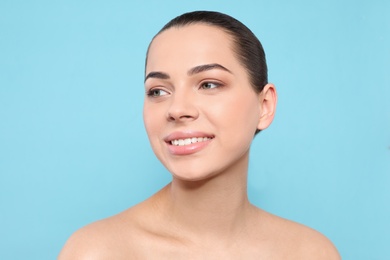 Photo of Portrait of young woman with beautiful face and natural makeup on color background