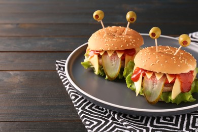Photo of Cute monster burgers on wooden table, space for text. Halloween party food