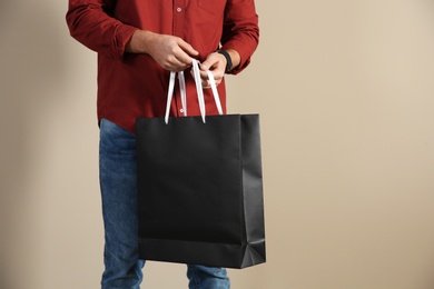 Young man holding paper bag on color background, closeup.  Mockup for design