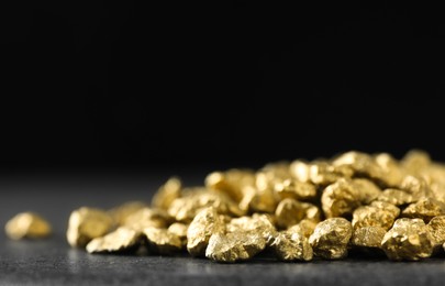 Photo of Shiny gold nuggets on grey surface, closeup. Space for text