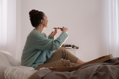 Woman with pizza watching movie via video projector at home