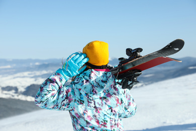Woman with ski equipment at mountains, back view. Winter vacation