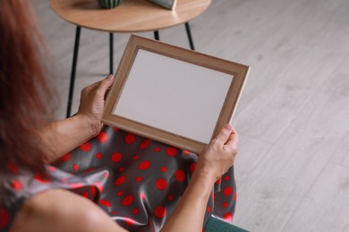 Photo of Woman holding empty photo frame indoors, closeup