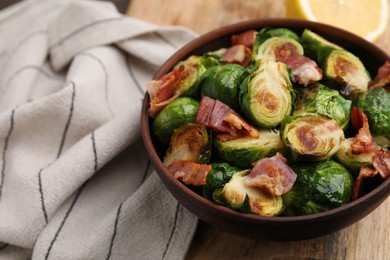 Photo of Delicious roasted Brussels sprouts and bacon in bowl on table, closeup