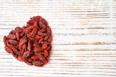 Photo of Dried goji berries on white wooden table, top view. Space for text