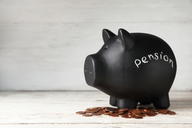 Piggy bank with word PENSION and coins on table. Space for text