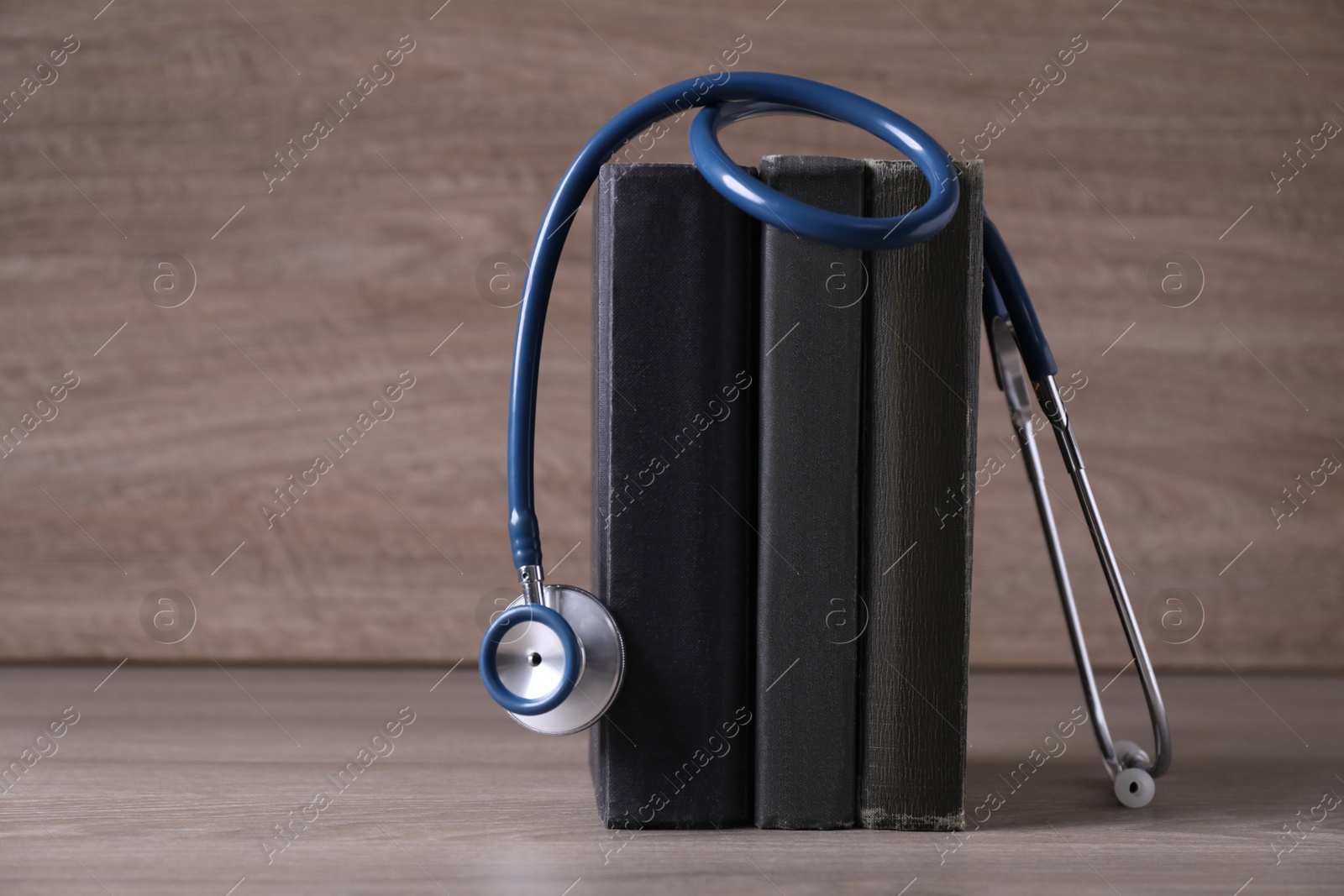 Photo of Student textbooks and stethoscope on wooden table. Medical education