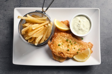 Photo of Plate with British traditional fish and potato chips on grey table, top view