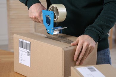 Seller taping parcel at workplace in office, closeup. Online store