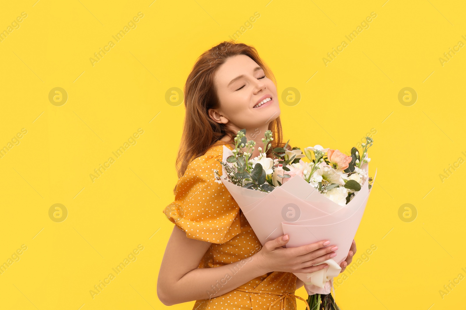 Photo of Happy woman with bouquet of beautiful flowers on yellow background