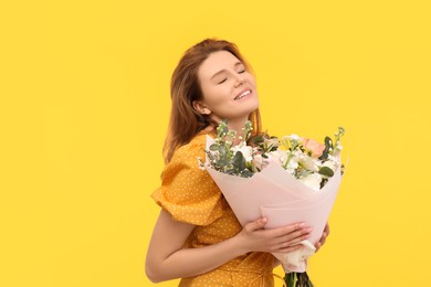 Photo of Happy woman with bouquet of beautiful flowers on yellow background