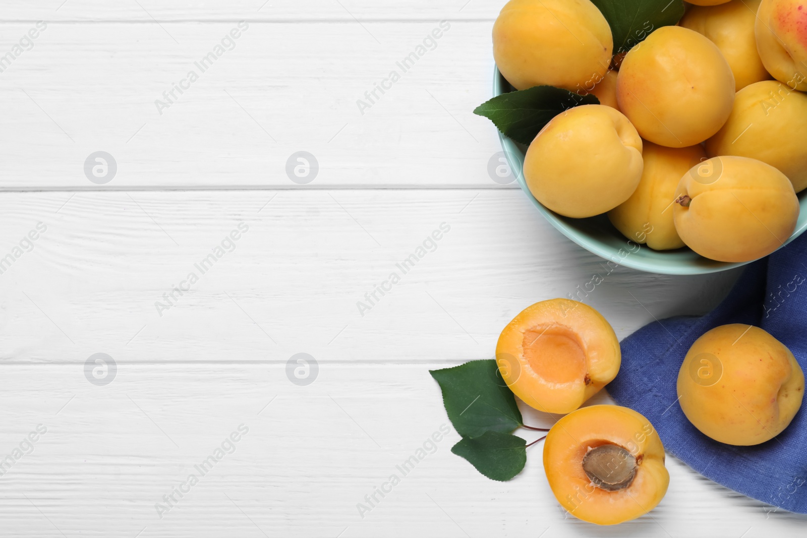 Photo of Delicious fresh ripe apricots on white wooden table, flat lay. Space for text