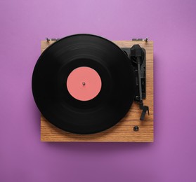 Photo of Modern turntable with vinyl record on purple background, top view