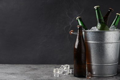 Metal bucket with beer and ice cubes on grey background. Space for text