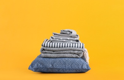 Photo of Stack of clean bed sheets and pillow on yellow background