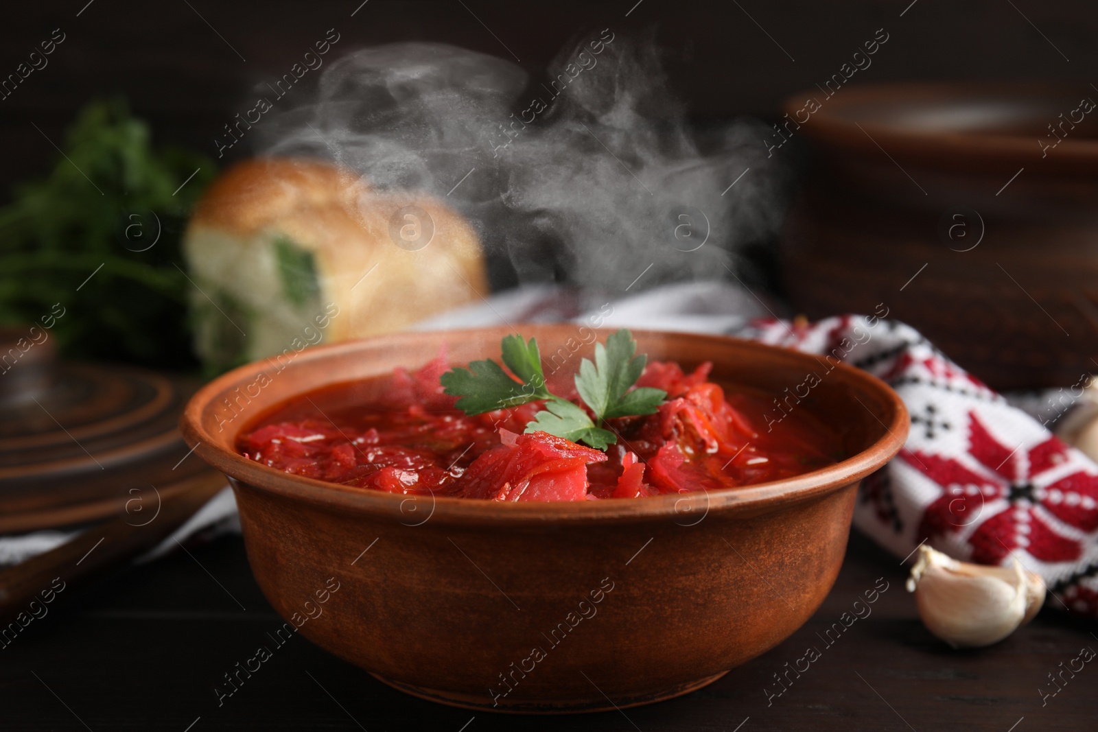 Image of Stylish brown clay bowl with Ukrainian borsch served on wooden table