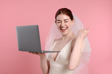 Photo of Cheerful bride with laptop on pink background