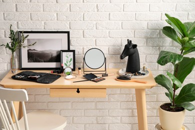 Dressing table with mirror, makeup products and accessories in room