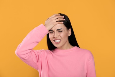 Photo of Woman suffering from migraine on yellow background