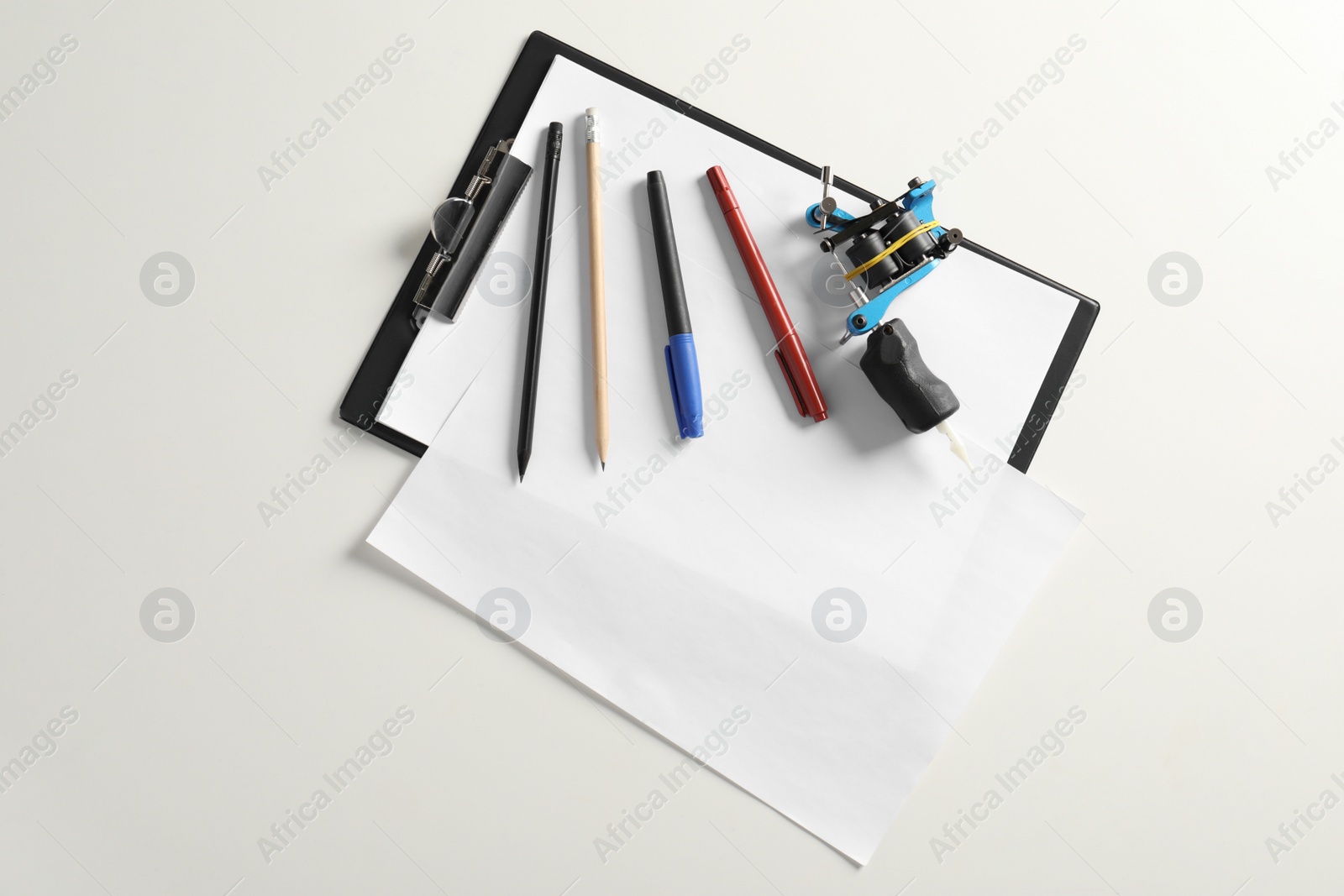 Photo of Composition with empty sheet of paper and tattoo machine on white background, top view. Space for text