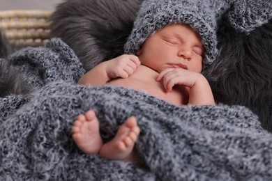 Photo of Adorable newborn baby lying in basket with faux fur