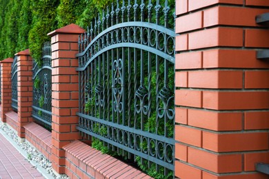 Photo of Beautiful brick fence with iron railing outdoors