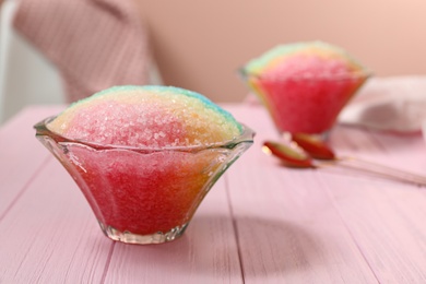 Photo of Rainbow shaving ice in glass dessert bowls on pink wooden table indoors