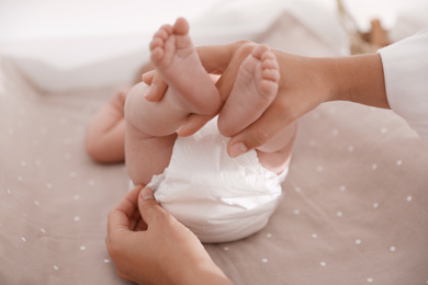 Photo of Mother changing her baby's diaper on table, closeup
