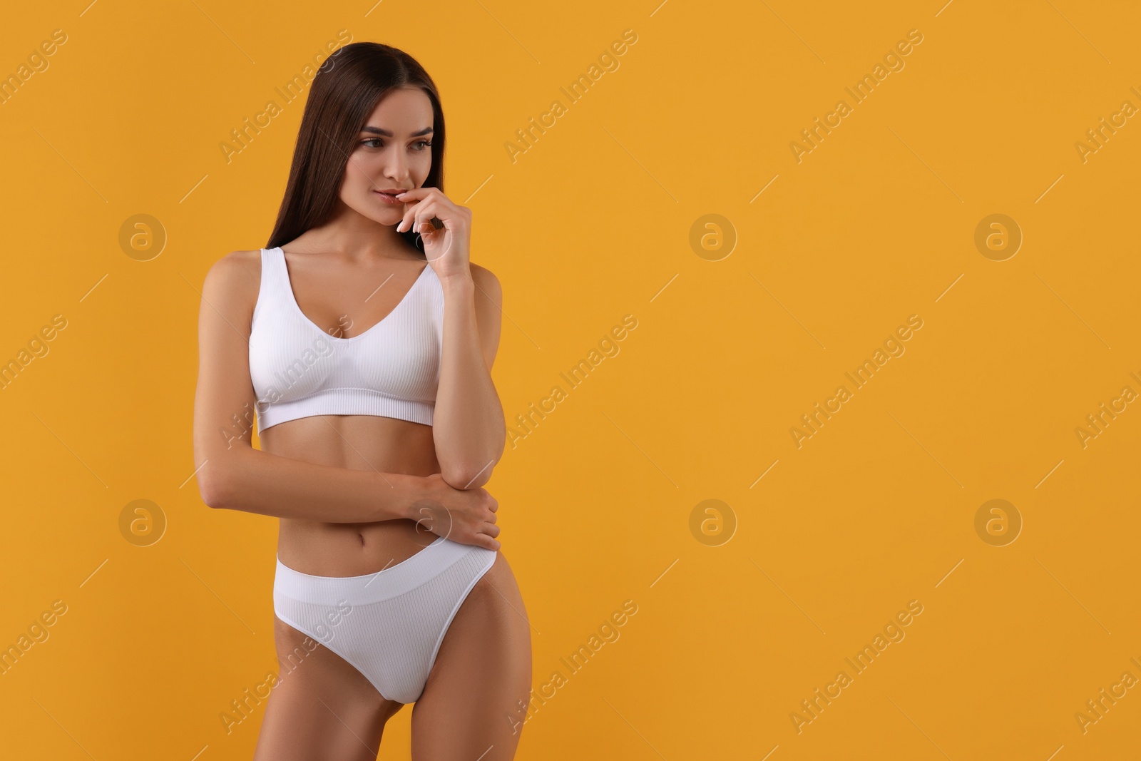 Photo of Young woman in stylish white bikini on orange background. Space for text