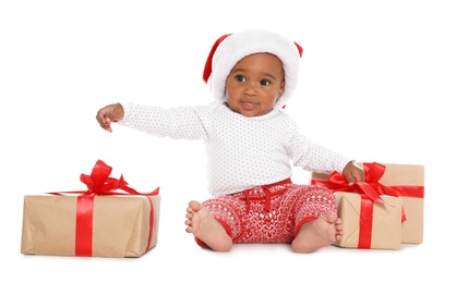 Festively dressed African-American baby with Christmas gifts on white background