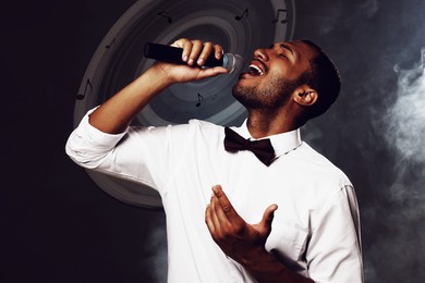 Image of Singer's performance poster, stylish design. Man with microphone on dark background