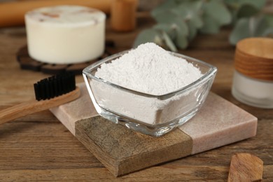 Photo of Tooth powder and brush on wooden table, closeup