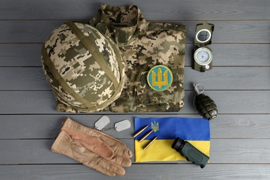 Photo of MYKOLAIV, UKRAINE - SEPTEMBER 26, 2020: Tactical gear, military uniform and Ukrainian flag on grey table, flat lay