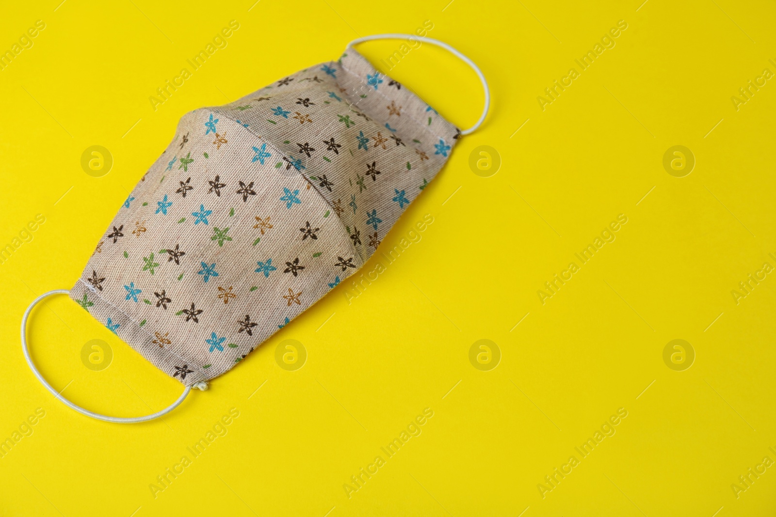 Photo of Homemade protective face mask on yellow background. Space for text