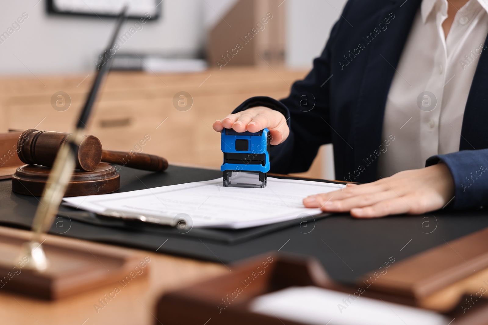 Photo of Notary stamping document at table in office, closeup