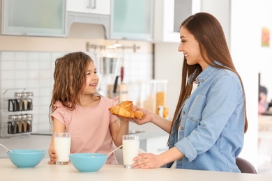 Mother and daughter having breakfast with milk at table