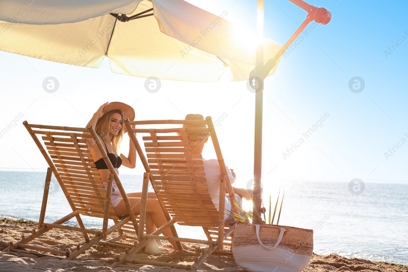 Photo of Couple relaxing on deck chairs at sandy beach. Summer vacation