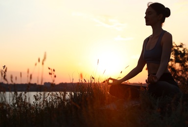 Photo of Young woman practicing yoga outdoors on sunset. Zen meditation