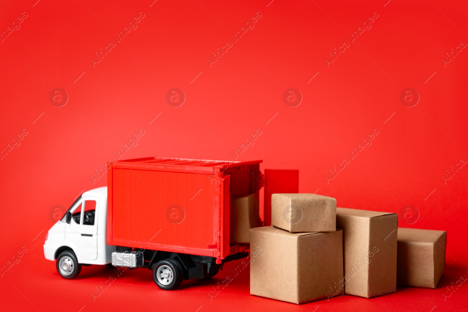 Photo of Toy truck with boxes on red background Logistics and wholesale concept
