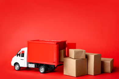 Photo of Toy truck with boxes on red background Logistics and wholesale concept