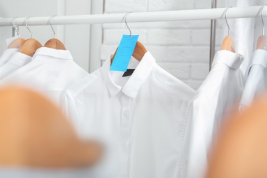 Photo of Rack with clean clothes on hangers after dry-cleaning indoors