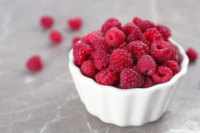 Photo of Bowl with ripe aromatic raspberries on table